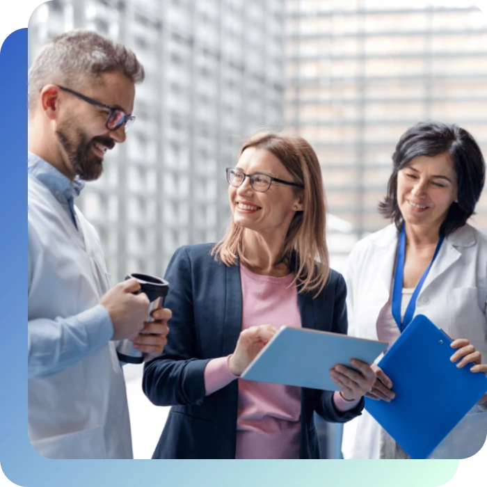 Ein Mann trinkt Kaffee, eine Frau hat ein Tablet und eine Frau hat ein Hefter in der Hand. Sie unterhalten sich.